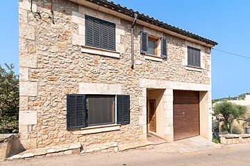 A stone building with black shutters on the windows
