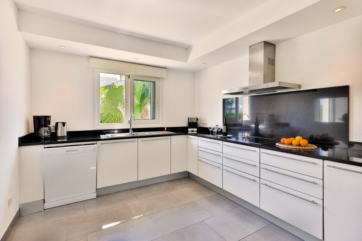 A kitchen with white cabinets and black counter tops