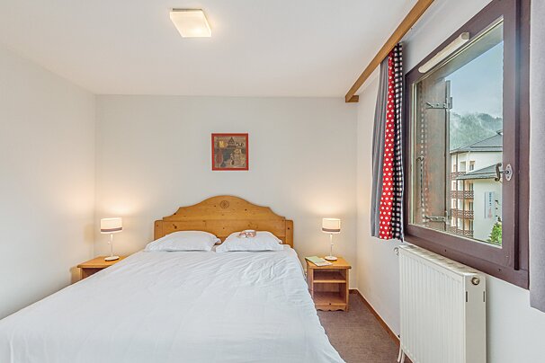 A small bedroom with a bed and a window