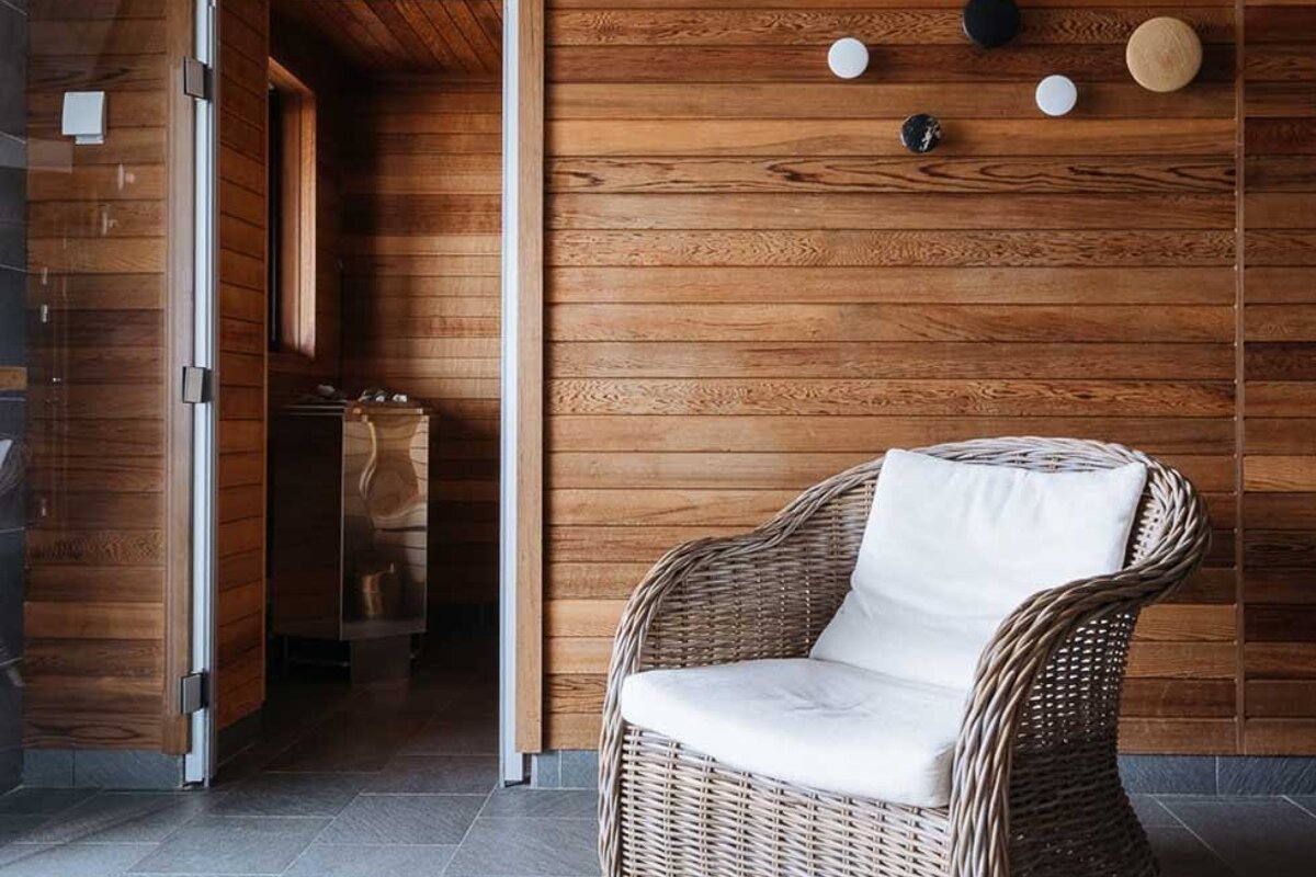 A wicker chair sits in front of a wooden wall