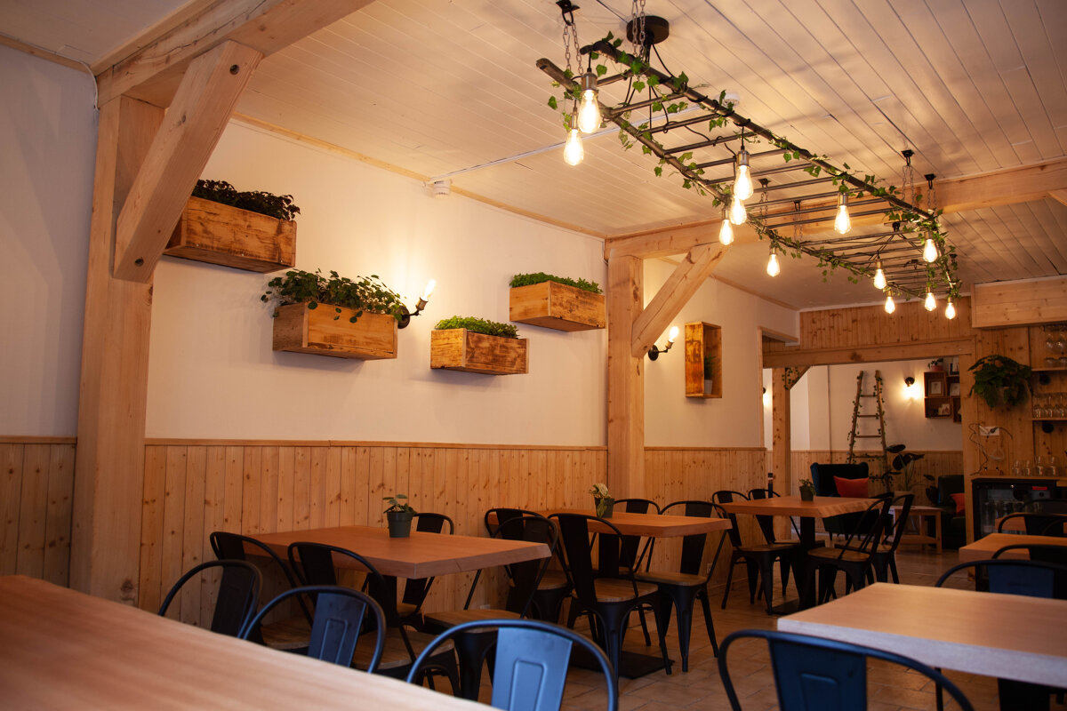 A restaurant with tables and chairs and a ladder hanging from the ceiling