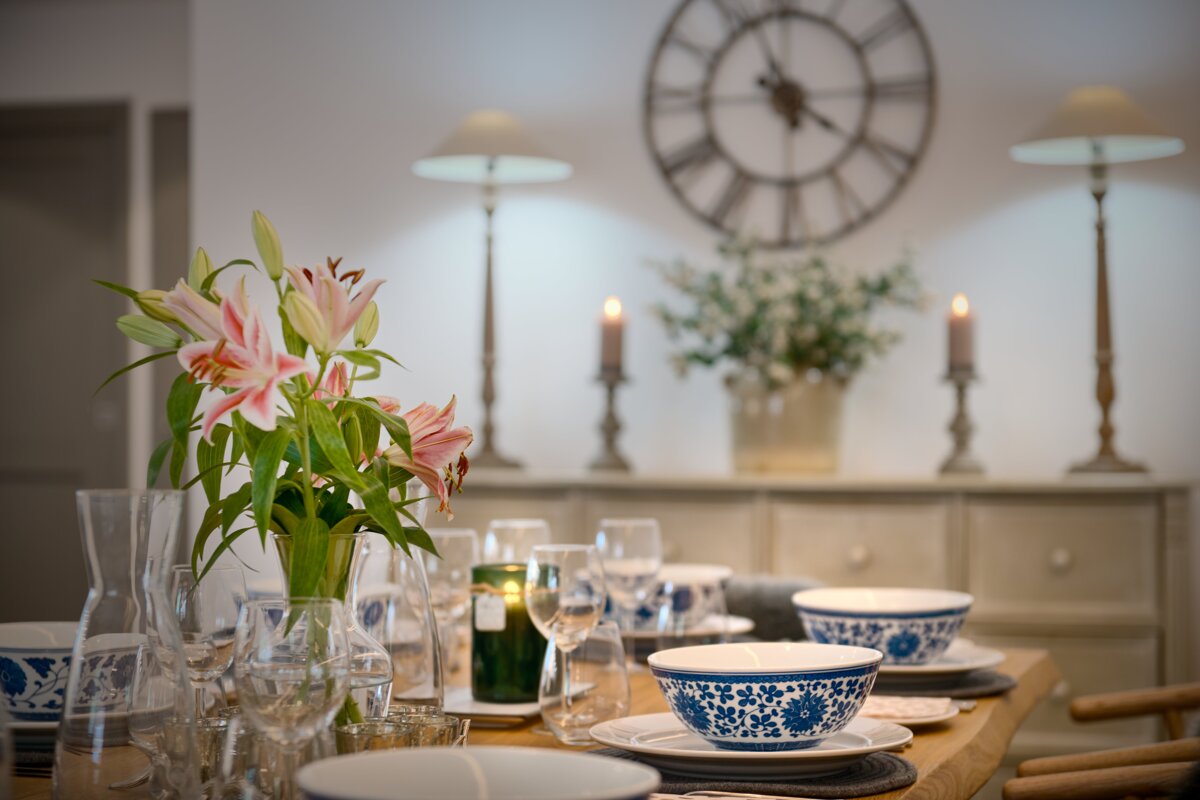A vase of flowers sits on a table in front of a clock