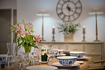 A vase of flowers sits on a table in front of a clock