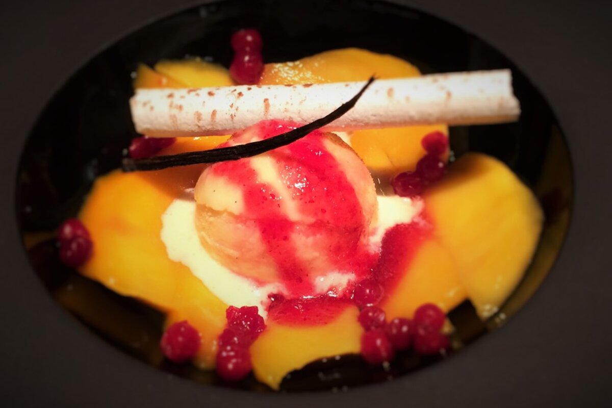 A close up of a dessert with a vanilla stick on top