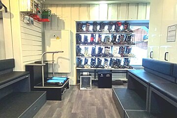 A ski boot fitting shop with numerous ski boots displayed on shelves, cushioned benches for trying them on, and a specialized boot fitting station.
