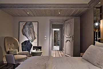 A bedroom with a chair and a painting on the wall