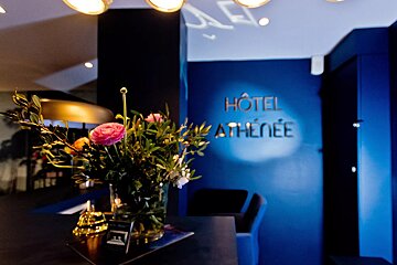 A vase of flowers sits in front of a sign that says hotel athenee