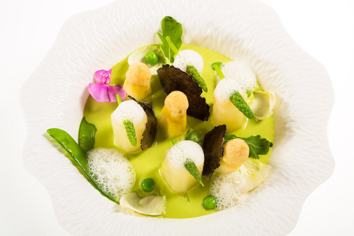 A white bowl filled with asparagus and other vegetables