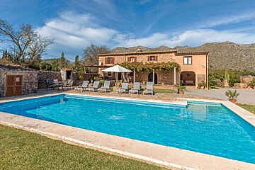 A large swimming pool in front of a house with mountains in the background