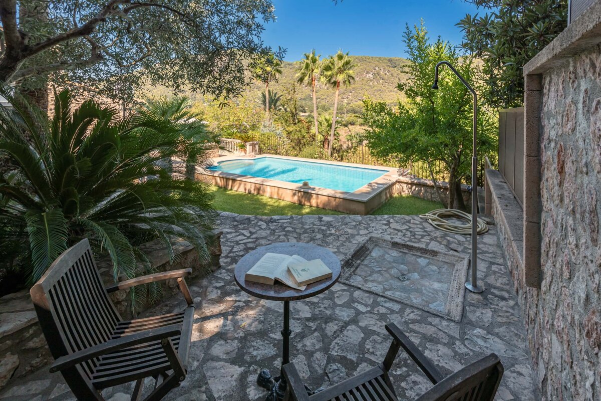 A book sits on a table in front of a swimming pool