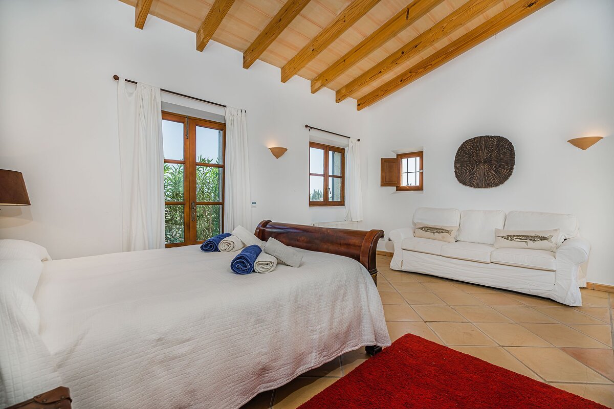 A bedroom with a bed a couch and a window