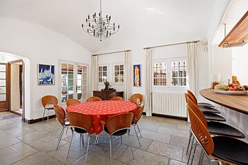 A dining room with a round table and chairs and a chandelier