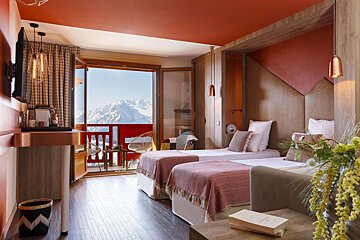 A hotel room with two beds and a balcony with mountains in the background