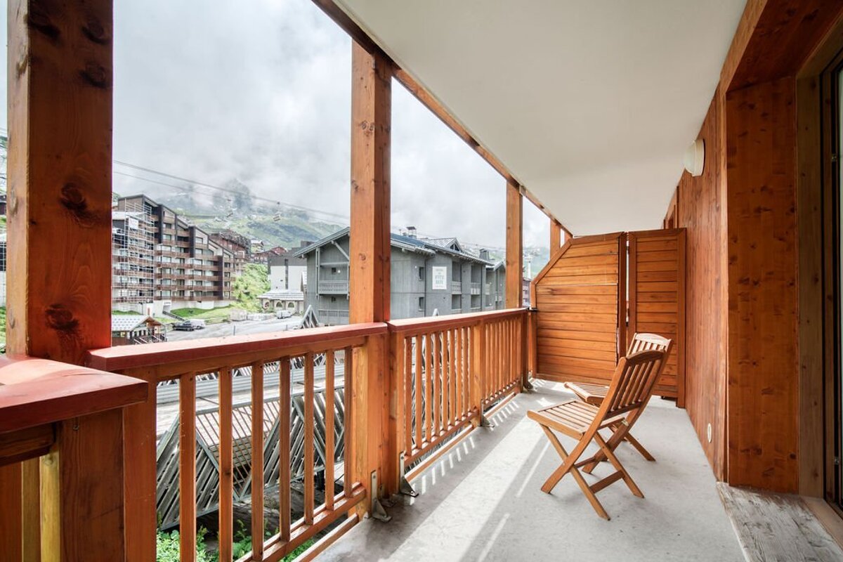A balcony with a chair and a view of a ski resort