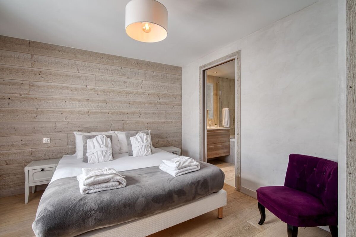 A bedroom with a large bed and a purple chair