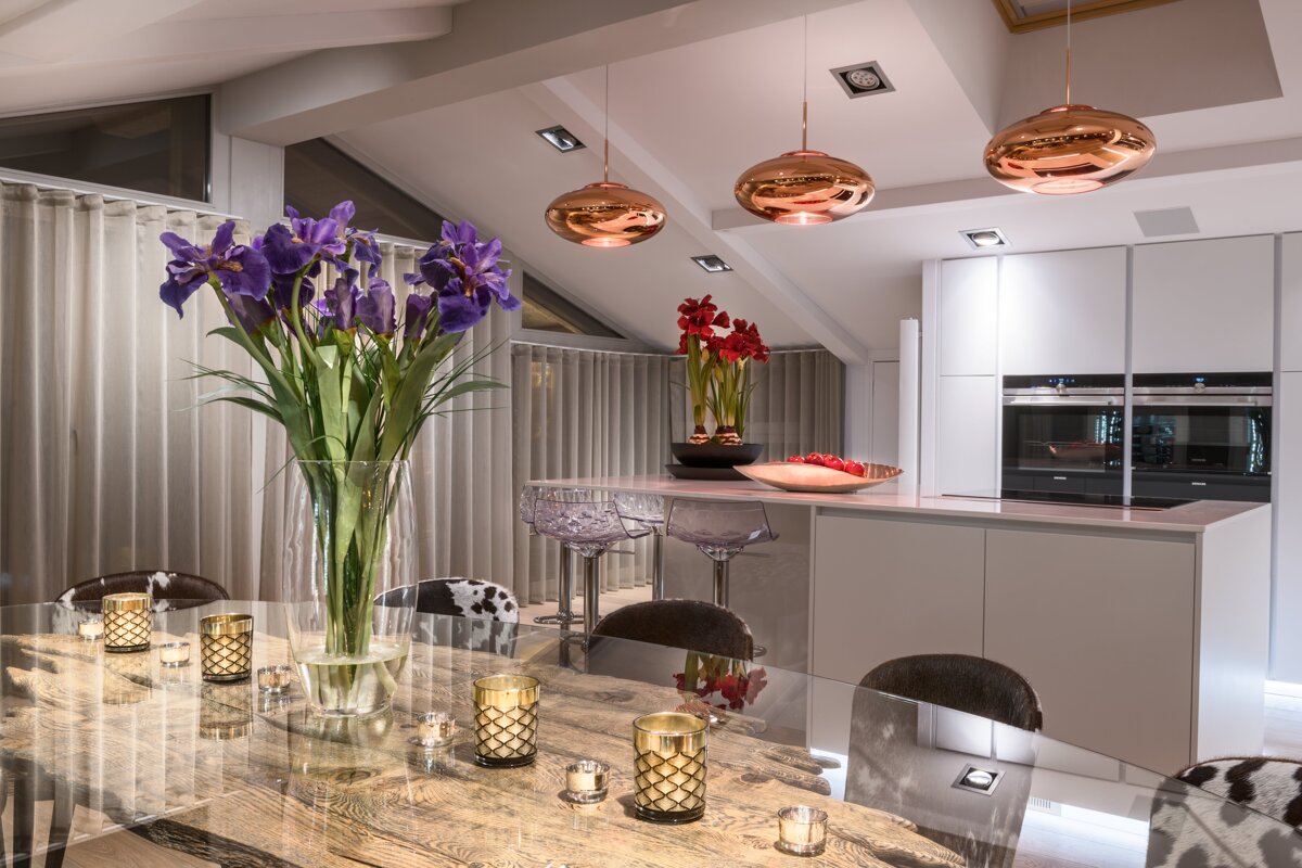 A vase of purple flowers sits on a table in a kitchen