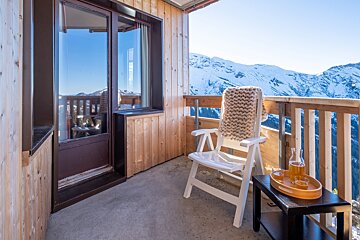 A balcony with a chair and a bottle of beer