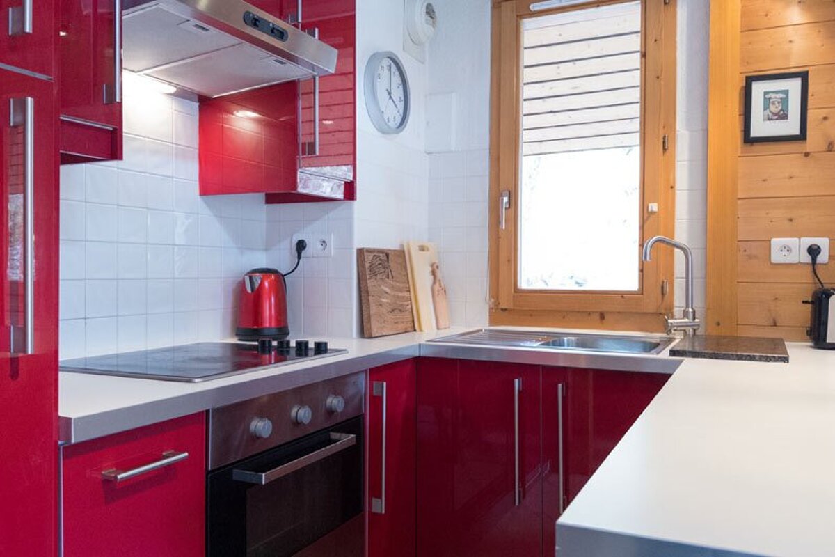A kitchen with red cabinets and a clock on the wall