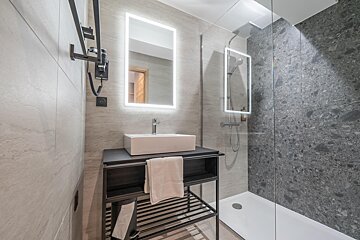 A bathroom with a sink a mirror and a walk in shower