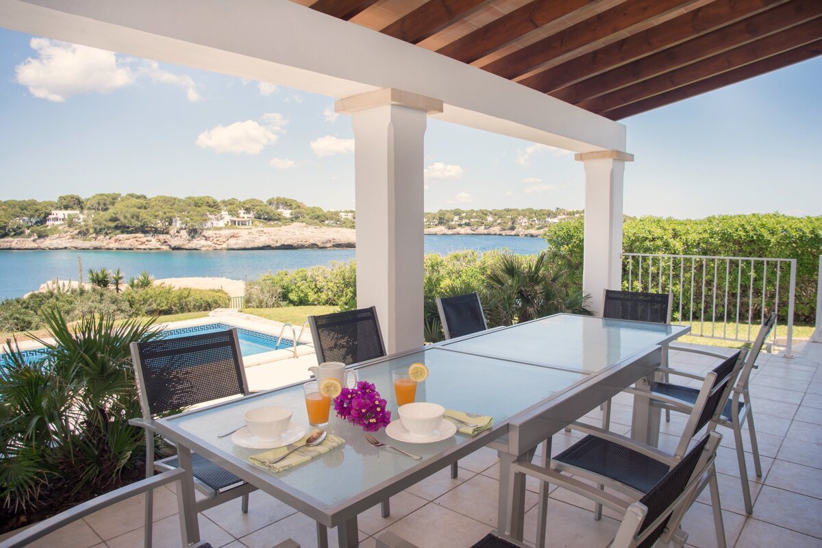 A patio with a table and chairs and a view of the ocean