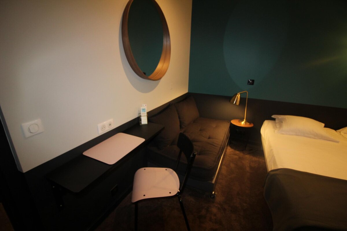 A hotel room with a couch and a desk