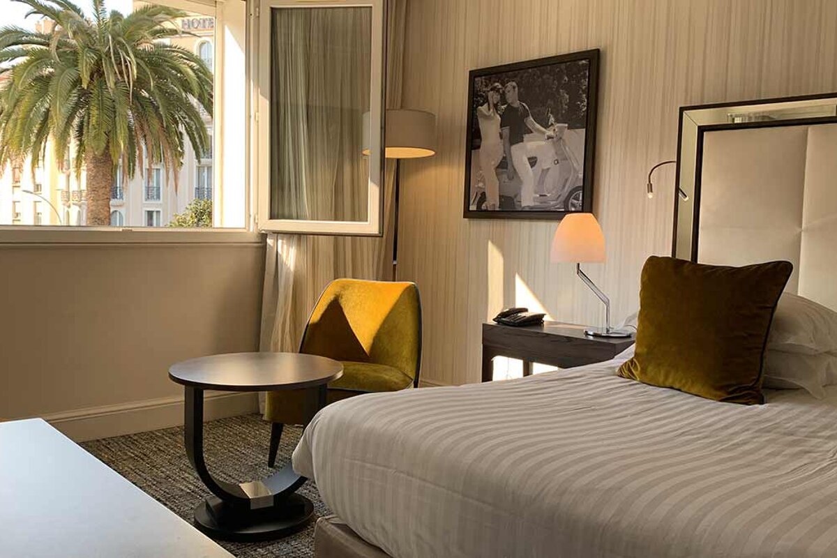 A hotel room with a palm tree in the window