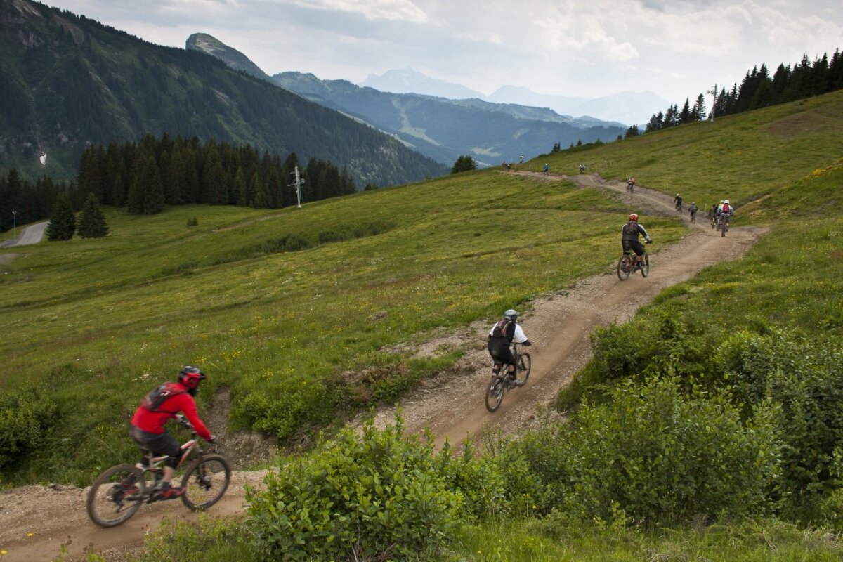 People riding bikes down a dirt road with mountains in the background