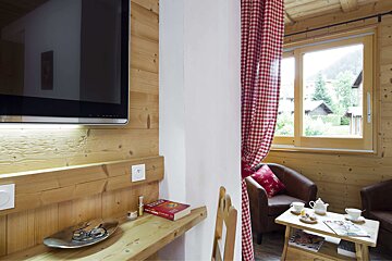 A red book on a wooden shelf next to a television