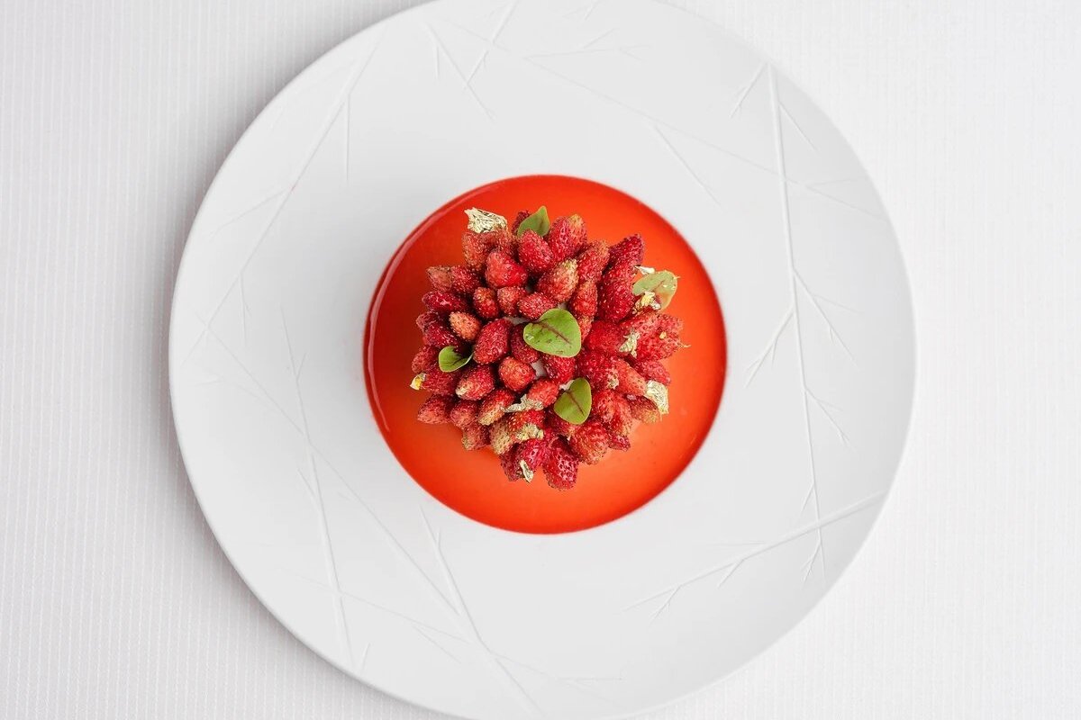 A white plate topped with strawberries and sauce
