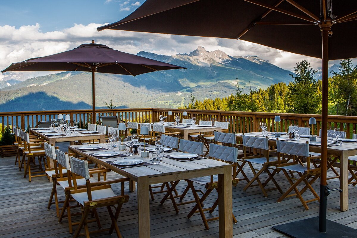 Tables and chairs on a deck with mountains in the background