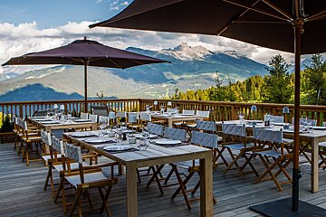 Tables and chairs on a deck with mountains in the background