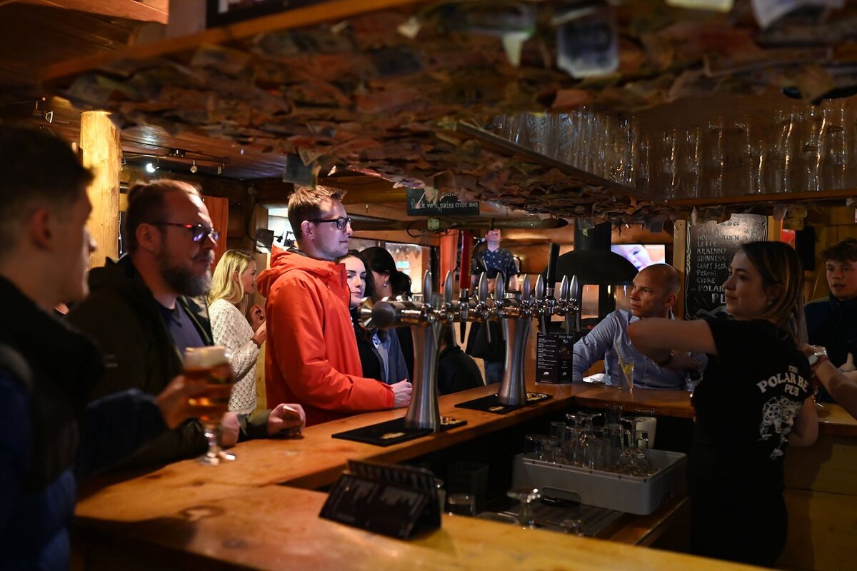 A bartender wearing a polar bear shirt pours beer