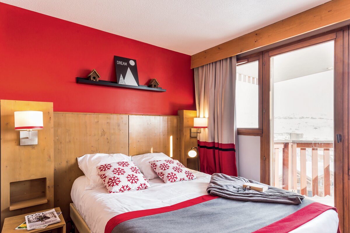 A bedroom with a red wall and a picture on the wall that says dream