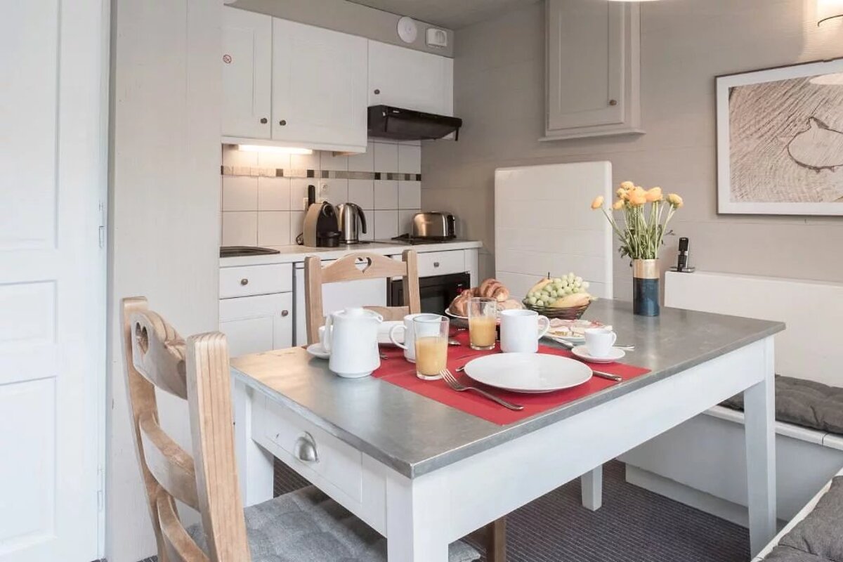 A small kitchen with a table and chairs set for breakfast
