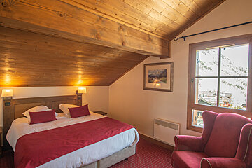 A bedroom with a bed a chair and a picture on the wall