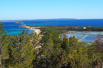 a view looking down to the beach of es cavallet & salt flats ibiza