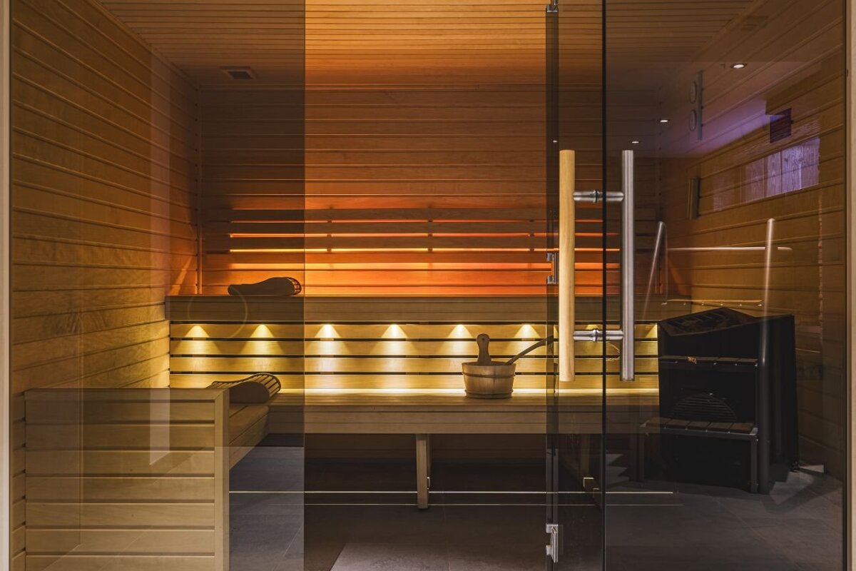 A sauna with a glass door and a bucket on the bench