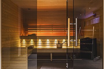 A sauna with a glass door and a bucket on the bench