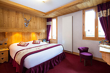 A bedroom with a large bed and a purple chair
