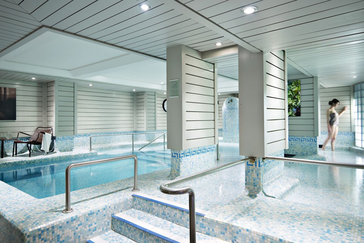 A woman in a bathing suit is standing next to a swimming pool