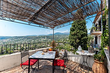 A table and chairs on a balcony with mountains in the background