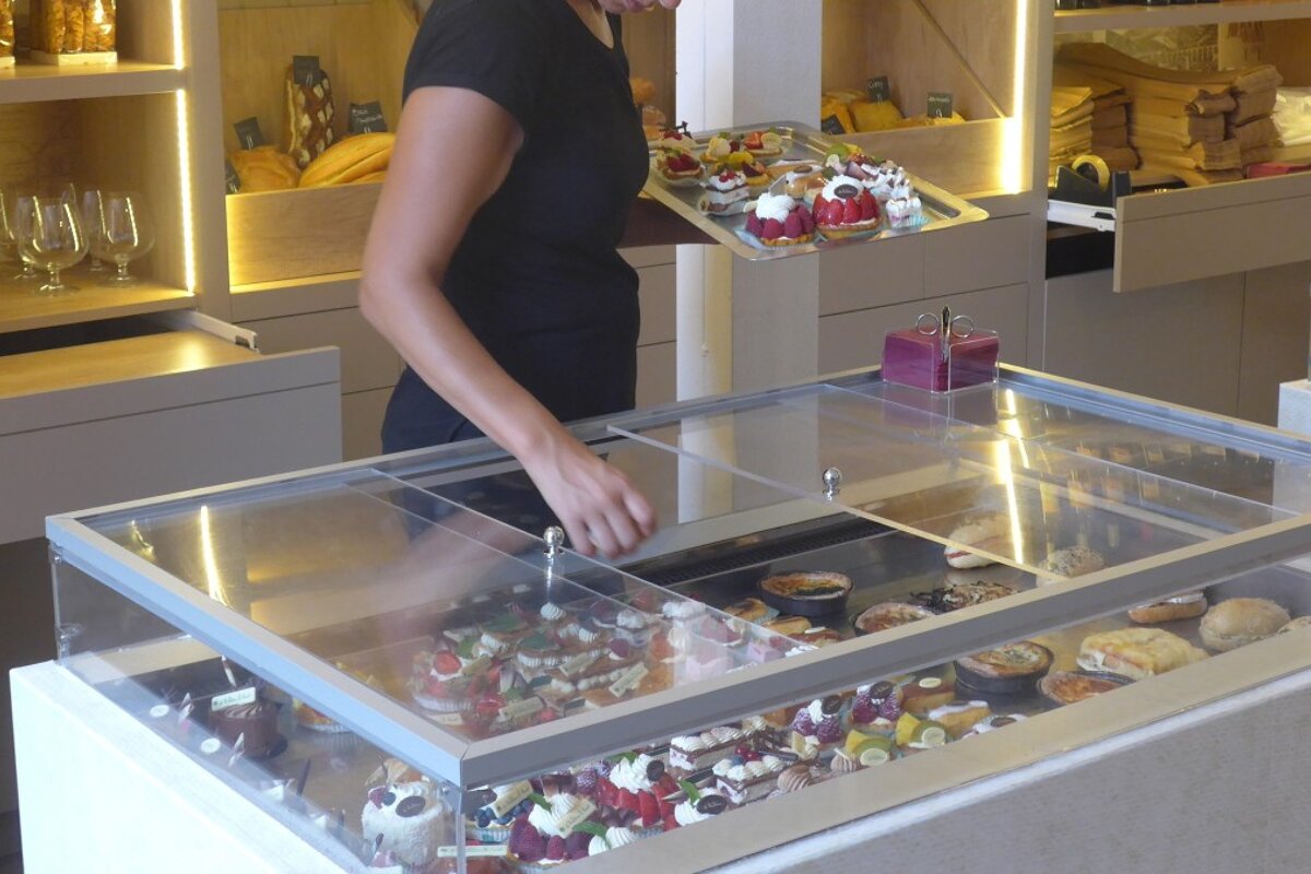 a woman looking at cakes in a glass case