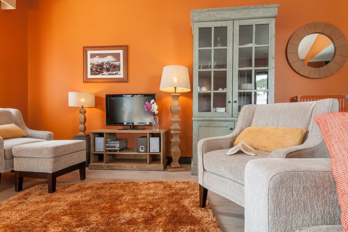 A living room with orange walls and a tv