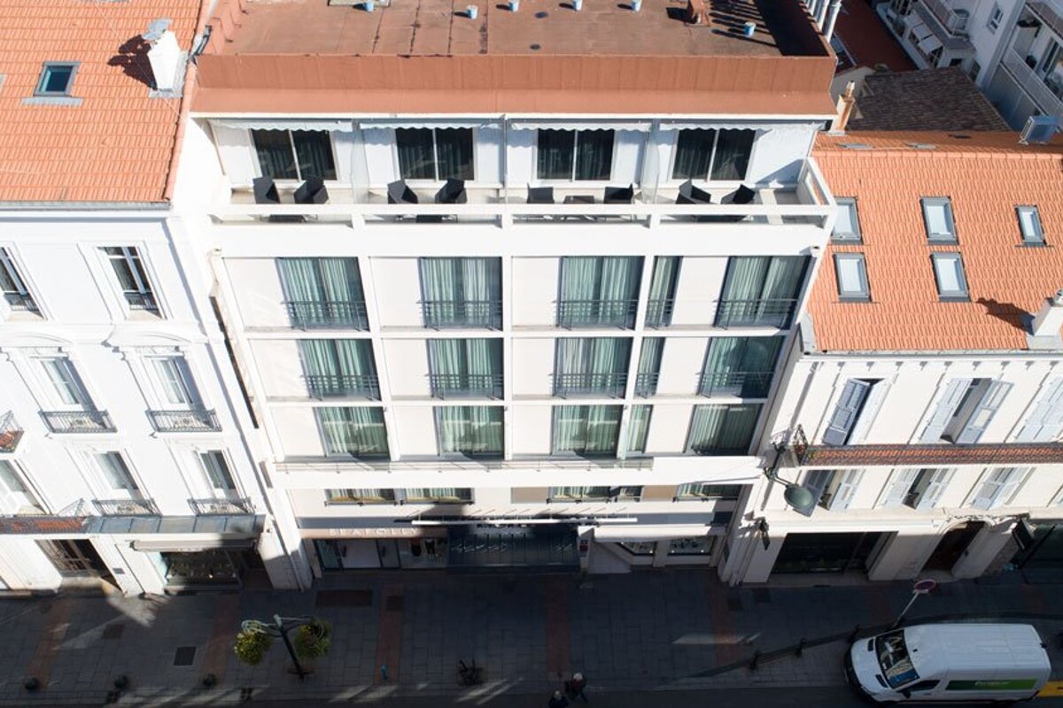 A white van is parked in front of a hotel