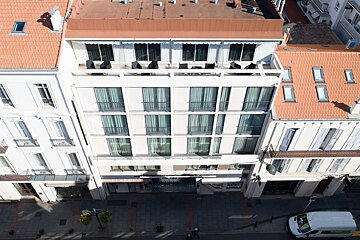 A white van is parked in front of a hotel