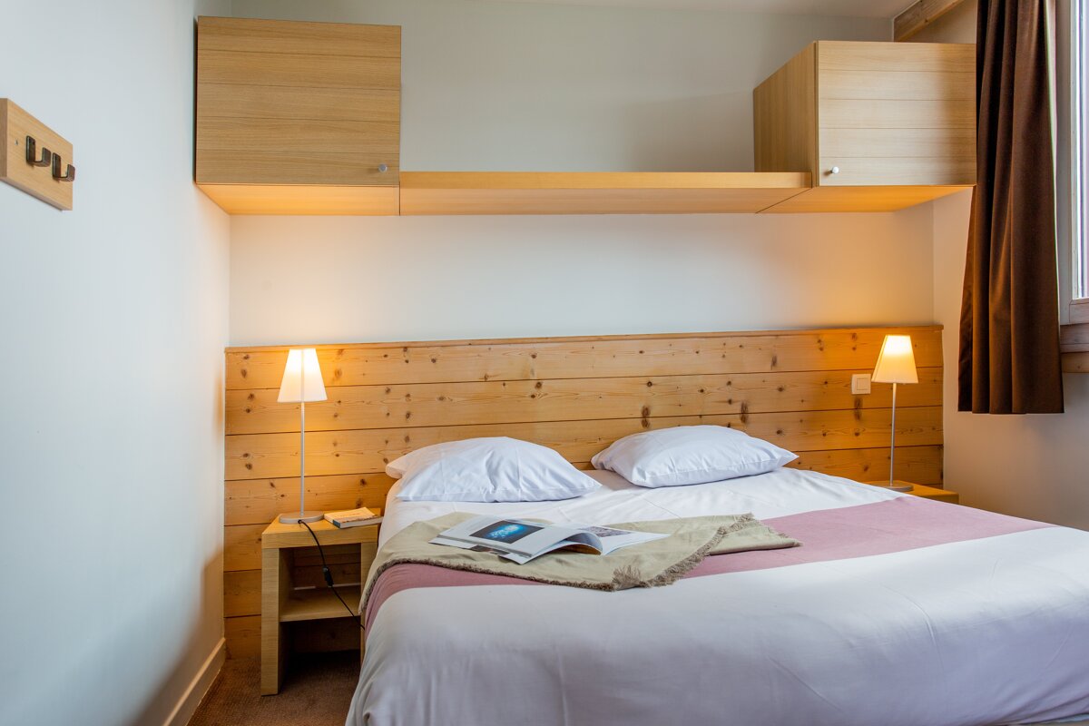 A bedroom with a wooden headboard and two lamps