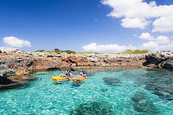 Two people in kayaks in a clear blue ocean