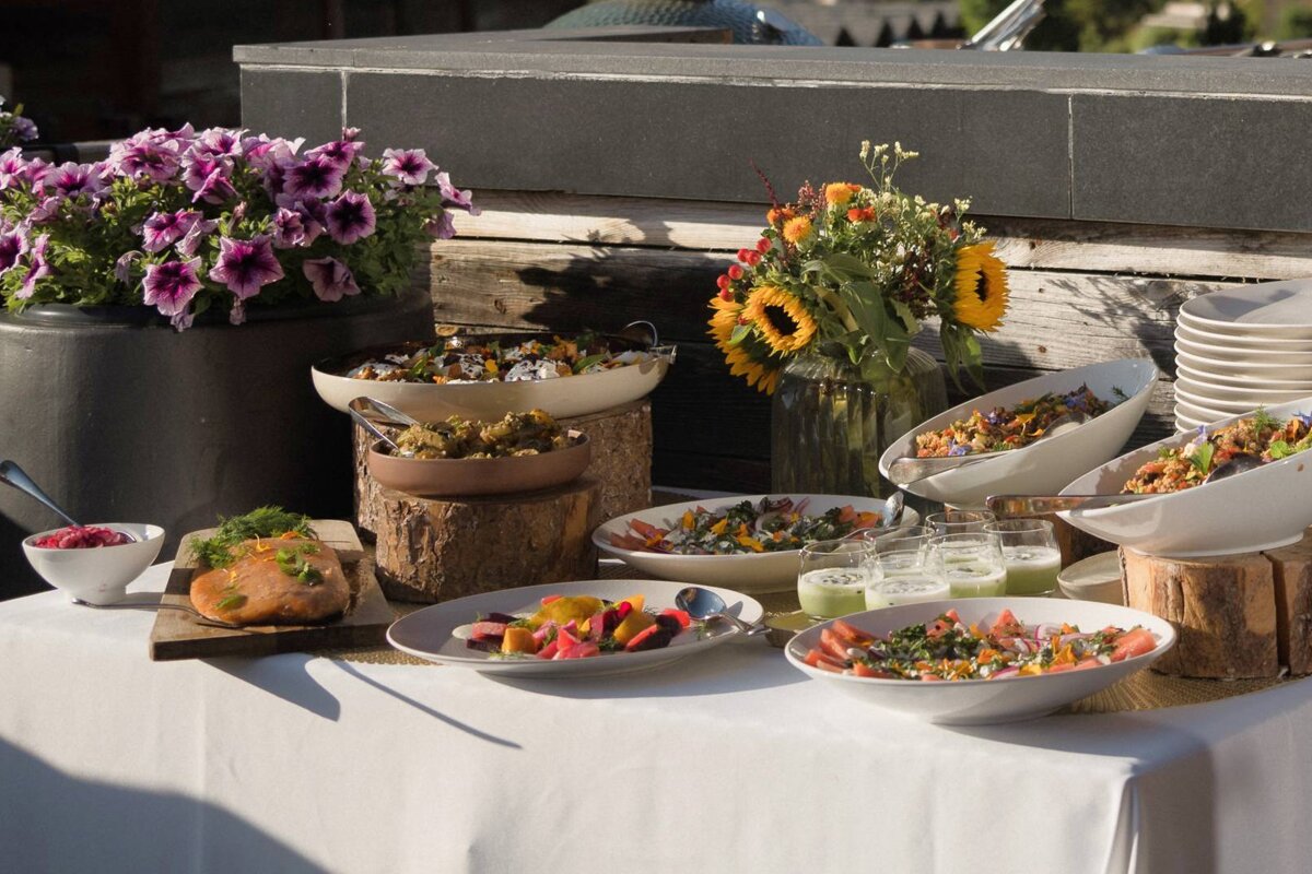 A buffet table with bowls of food and flowers in the background