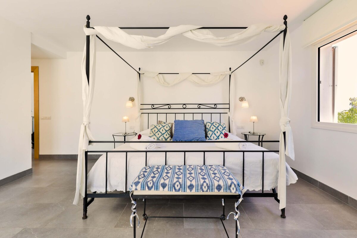 A bedroom with a canopy bed and a bench