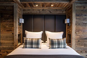 A bed with plaid pillows and a wooden headboard
